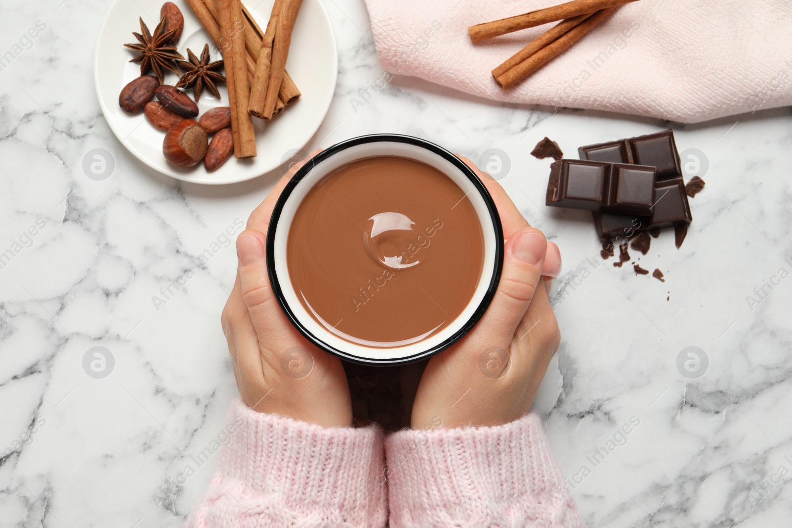 Photo of Woman with mug of yummy hot chocolate at white marble table, top view