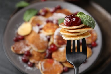 Photo of Fork with cereal pancakes, cranberries and mint on blurred background, closeup. Space for text