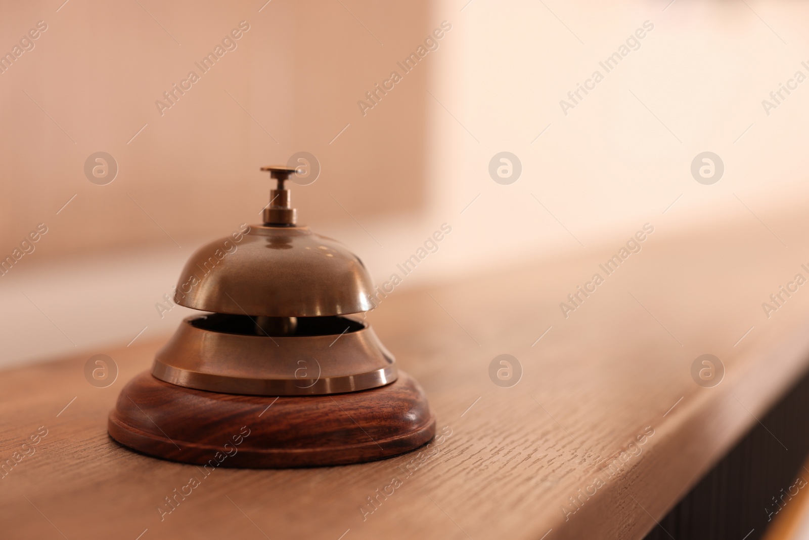 Photo of Hotel service bell on wooden reception desk. Space for text