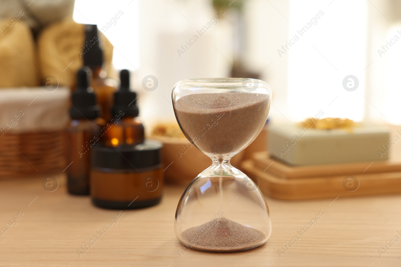 Photo of Sandglass on wooden table indoors, closeup. Spa time