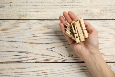 Photo of Woman with clothes pins at white wooden table, top view. Space for text