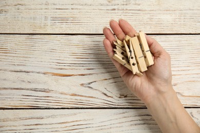 Woman with clothes pins at white wooden table, top view. Space for text