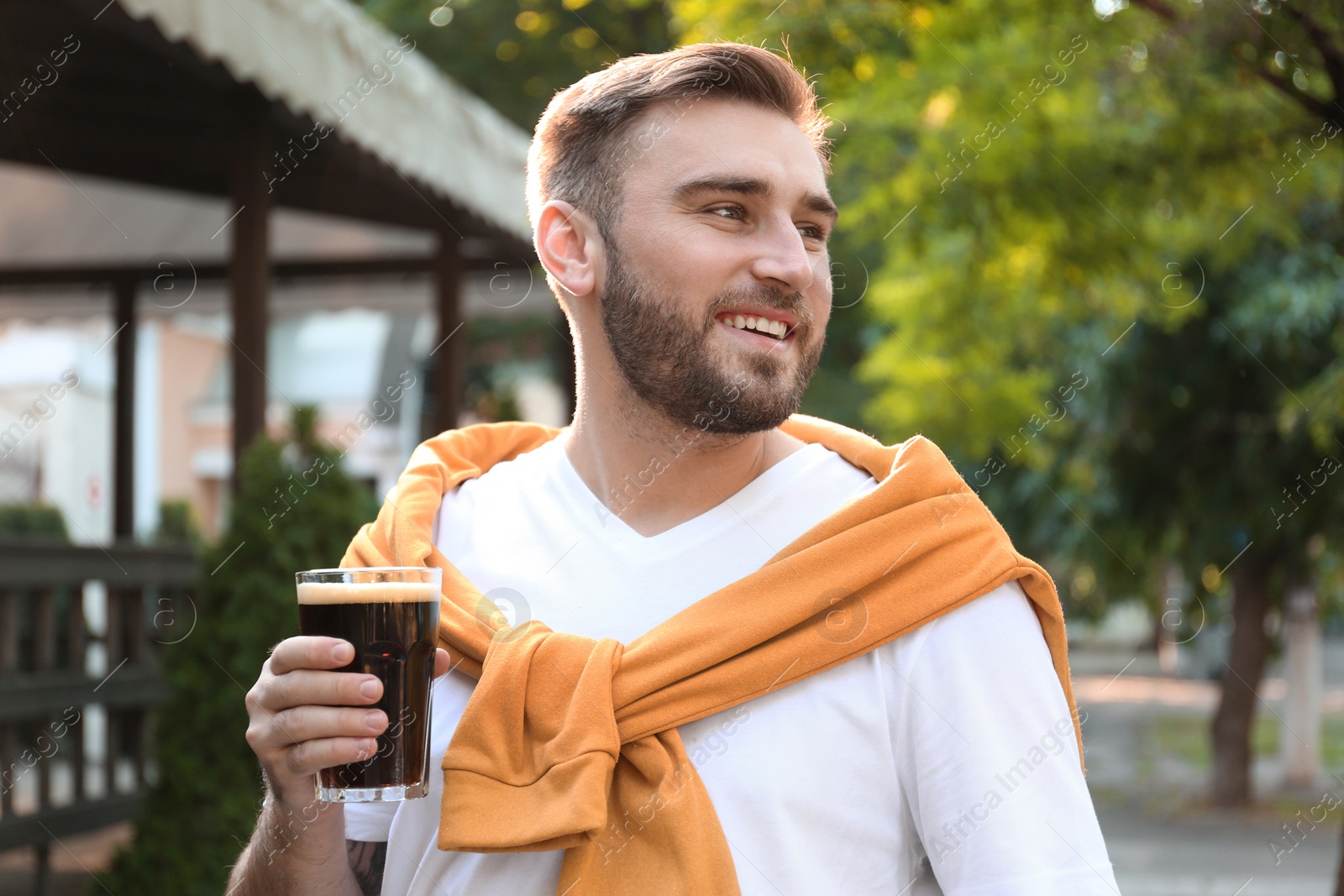 Photo of Handsome man with cold kvass outdoors. Traditional Russian summer drink