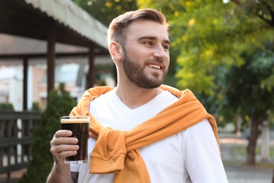 Photo of Handsome man with cold kvass outdoors. Traditional Russian summer drink