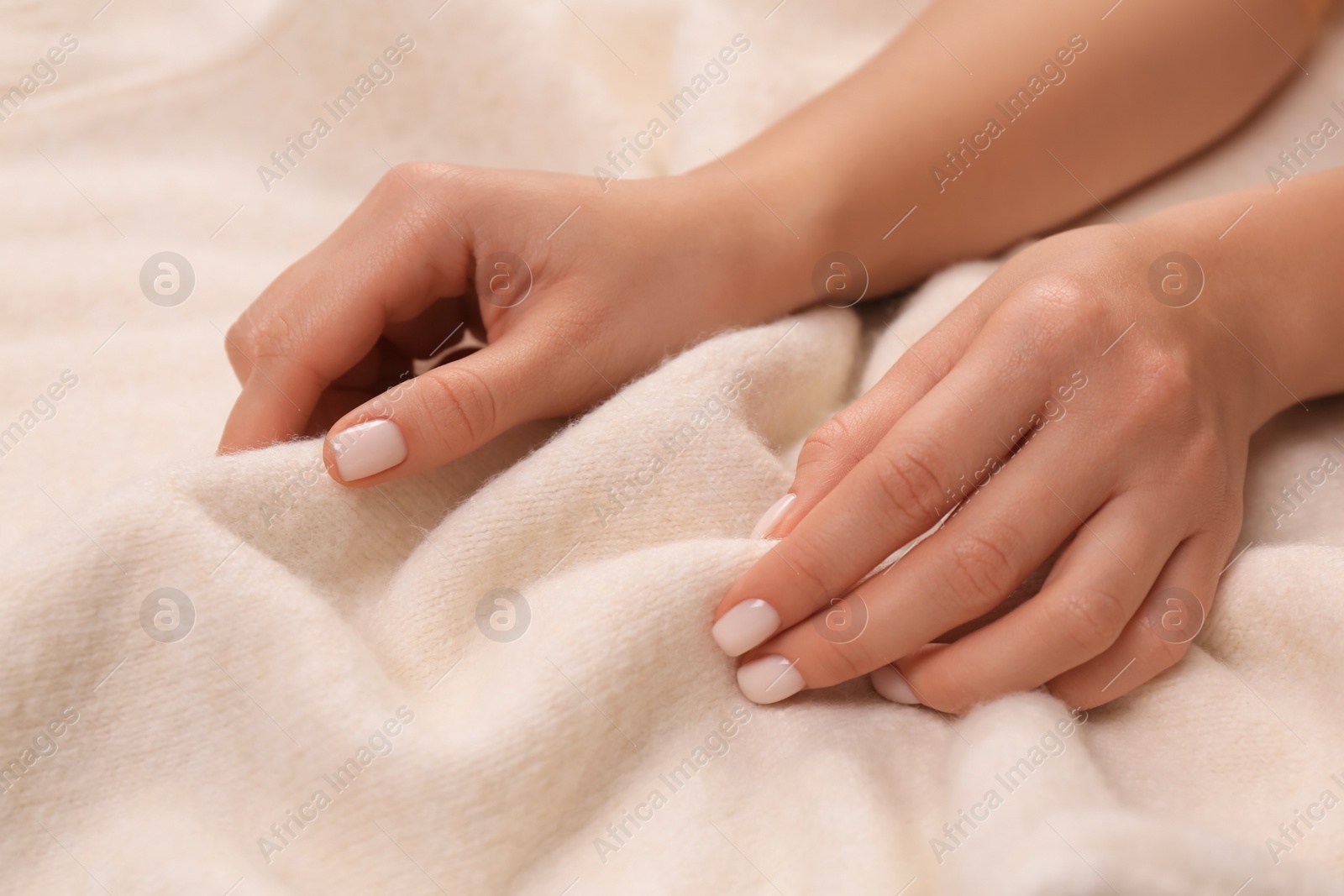 Photo of Woman touching soft beige knitted fabric, closeup