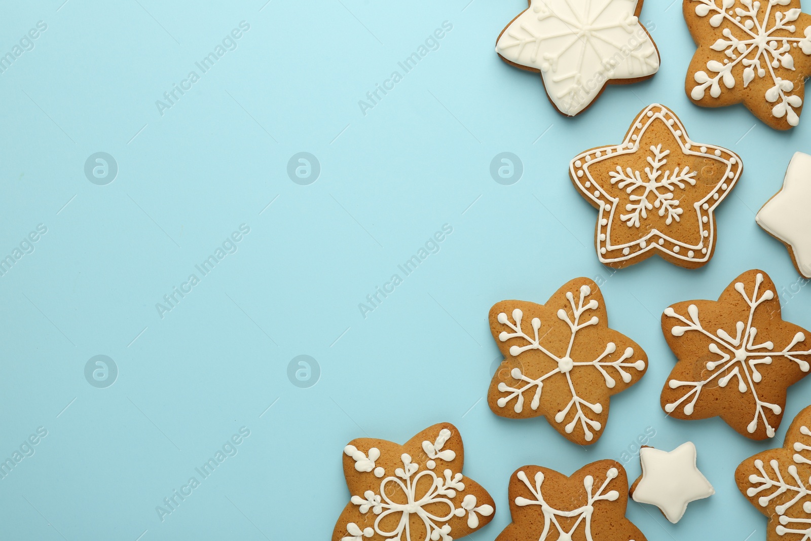 Photo of Tasty star shaped Christmas cookies with icing on light blue background, flat lay. Space for text