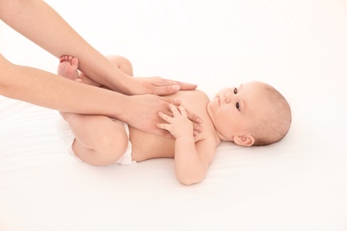 Photo of Mother and her cute child on white bed. Baby massage and exercises