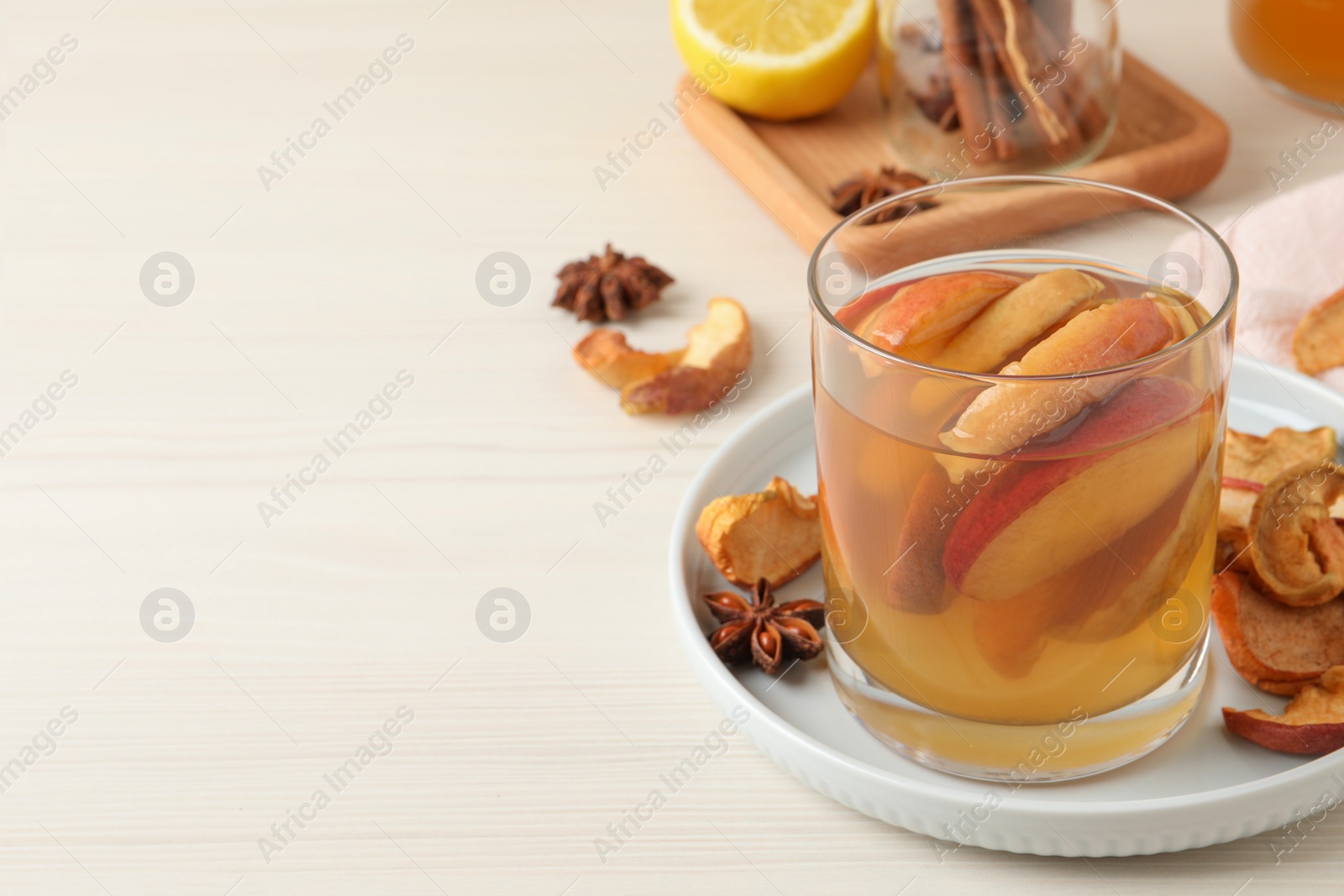 Photo of Delicious compot with dried apple slices on light wooden table. Space for text