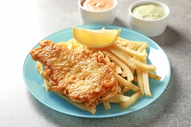 Photo of Plate with British Traditional Fish and potato chips on grey background