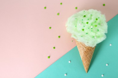 Photo of Sweet cotton candy in waffle cone on beige background, top view. Space for text