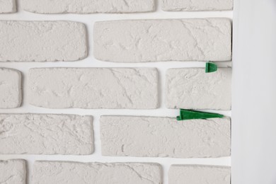 Photo of Decorative white bricks with tile leveling system on wall, closeup