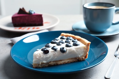 Photo of Plate with piece of tasty blueberry cake on gray table