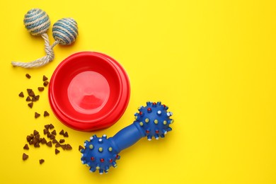 Pet toys, food and bowl on yellow background, flat lay. Space for text