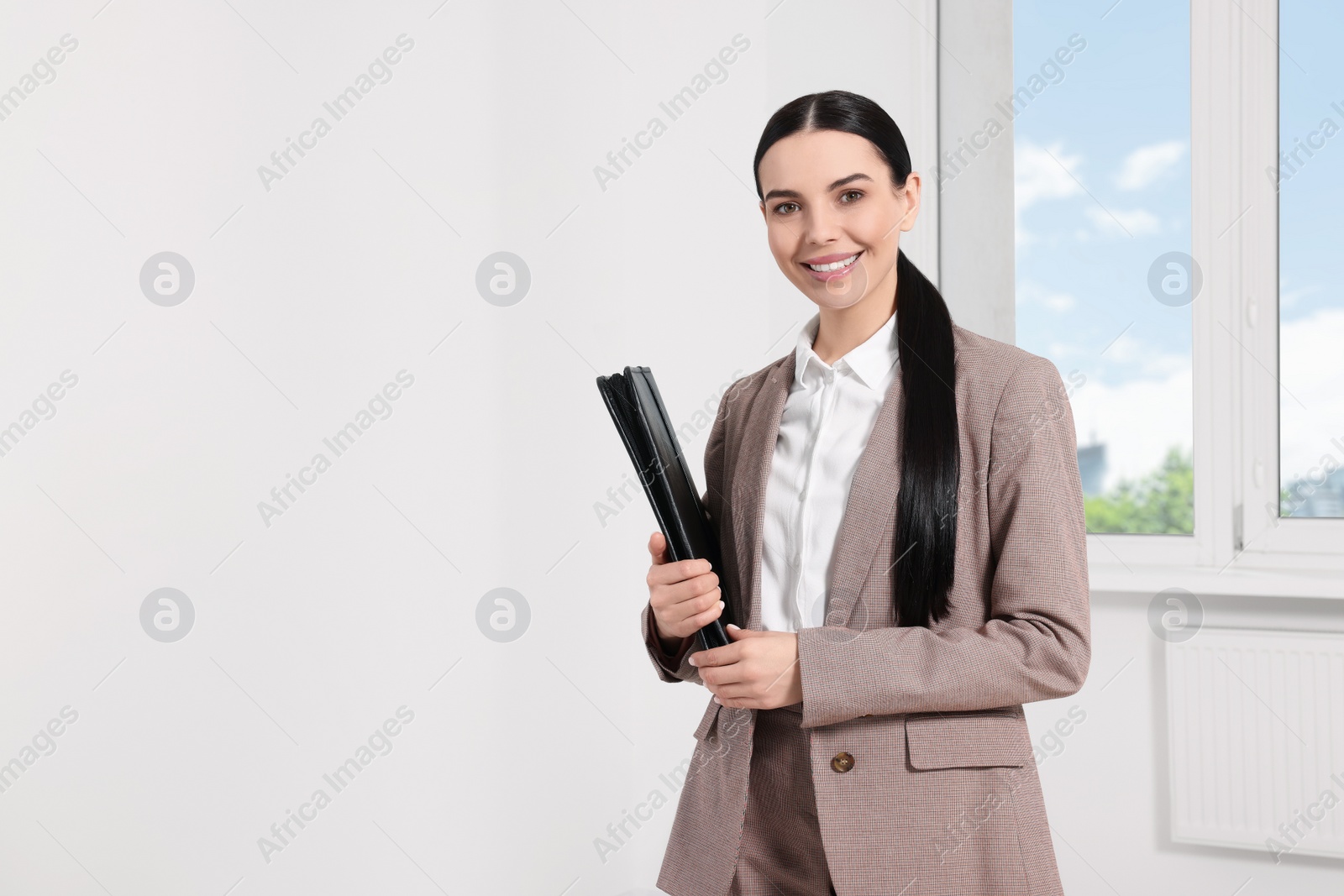 Photo of Beautiful real estate agent with documents indoors, space for text