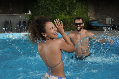 Happy couple having fun in outdoor swimming pool on sunny summer day