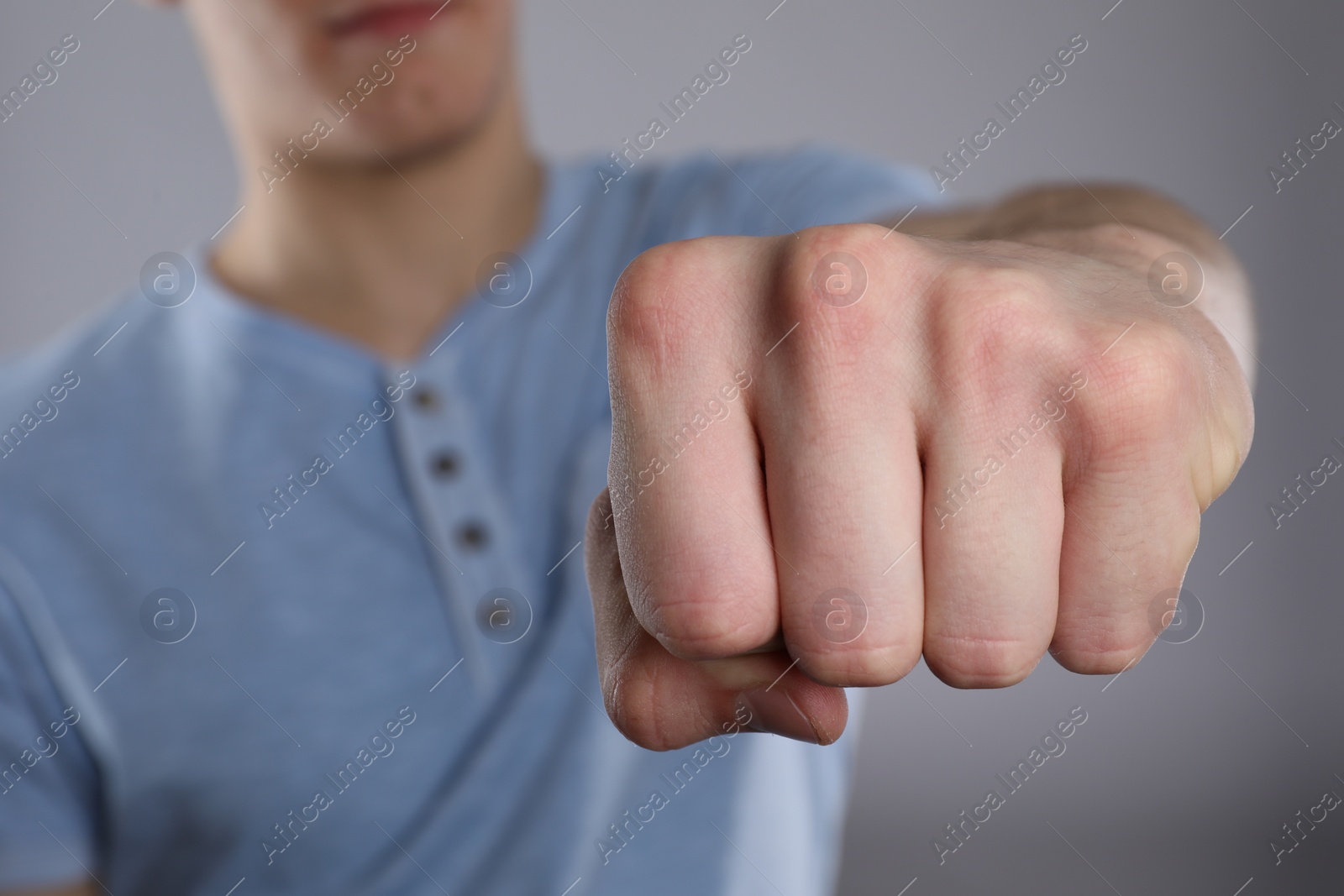 Photo of Man showing fist with space for tattoo on grey background, selective focus