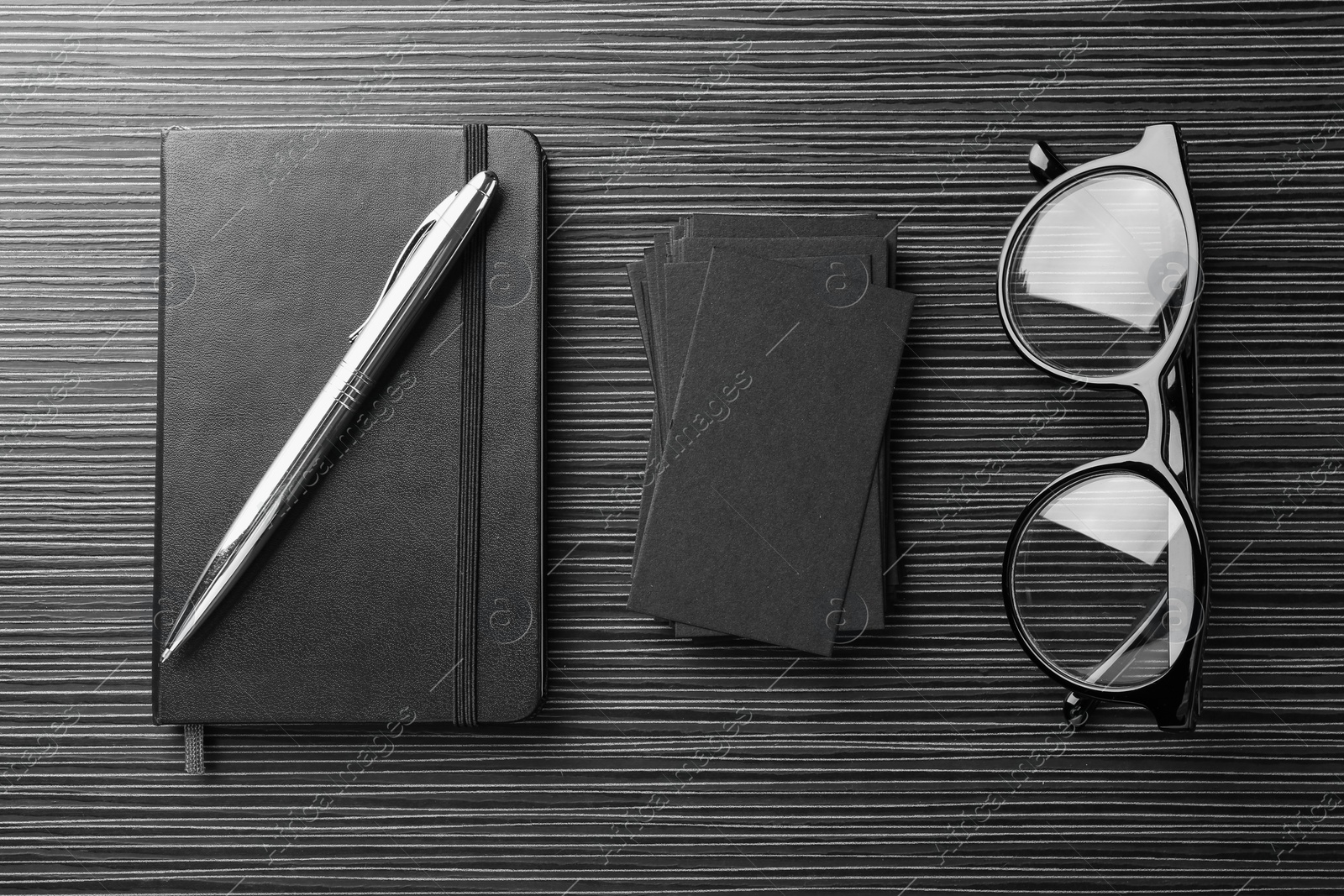 Photo of Blank black business cards, glasses and stationery on wooden table, flat lay. Mockup for design