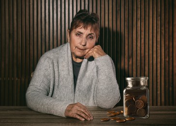 Image of Pension plan. Senior woman and coins near wooden wall