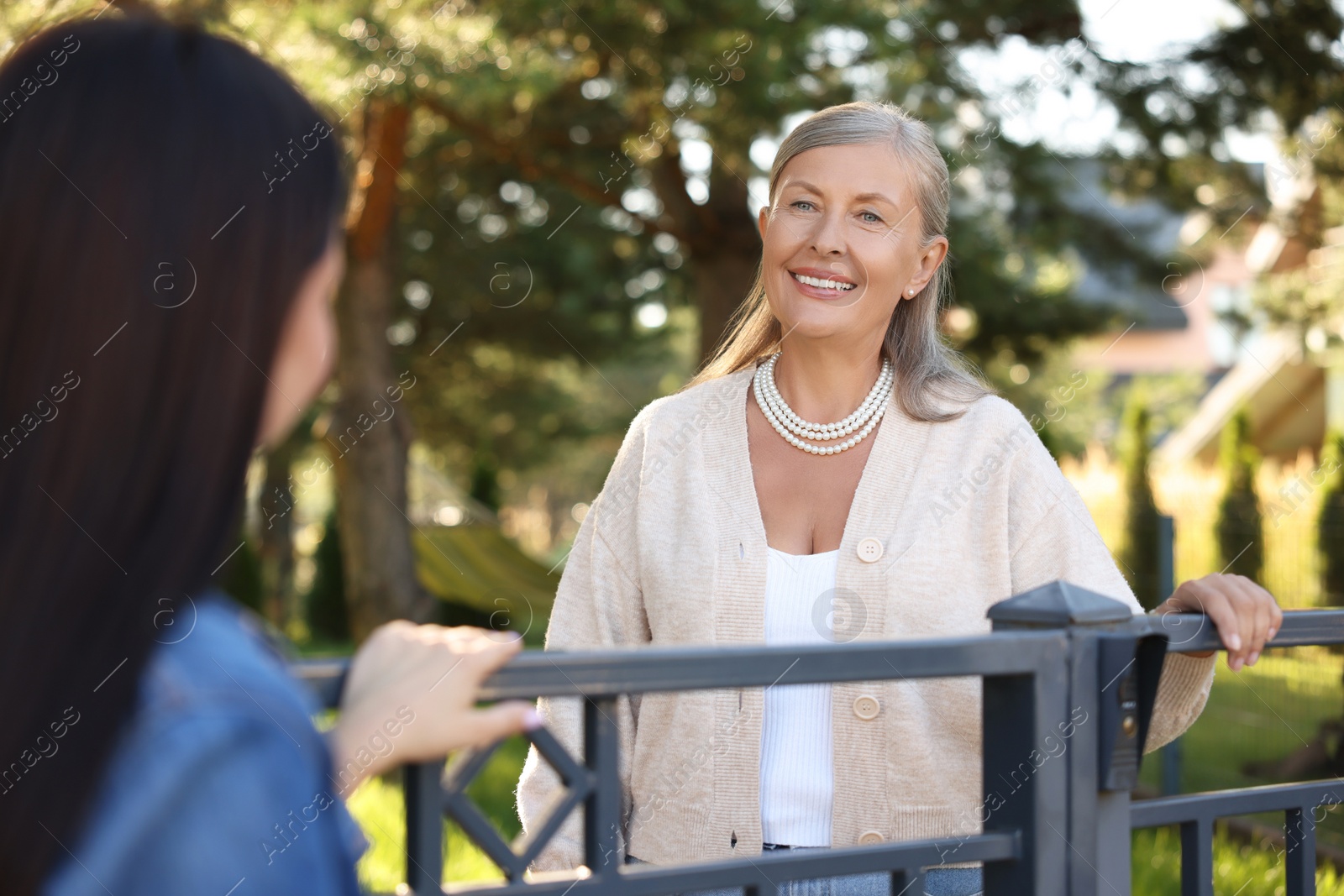 Photo of Friendly relationship with neighbours. Happy women near fence outdoors