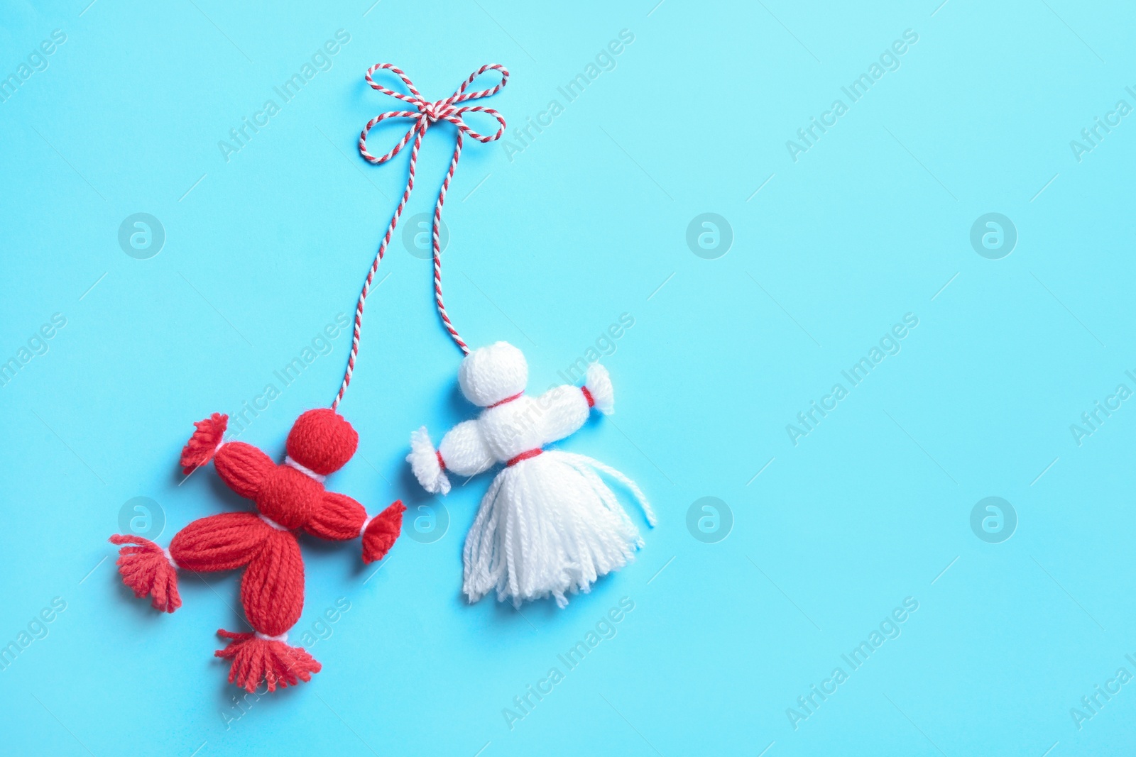 Photo of Traditional martisor shaped as man and woman on light blue background, top view with space for text. Beginning of spring celebration