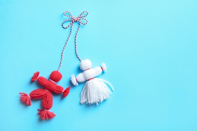 Photo of Traditional martisor shaped as man and woman on light blue background, top view with space for text. Beginning of spring celebration