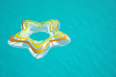 Star shaped inflatable ring floating in swimming pool on sunny day. Space for text