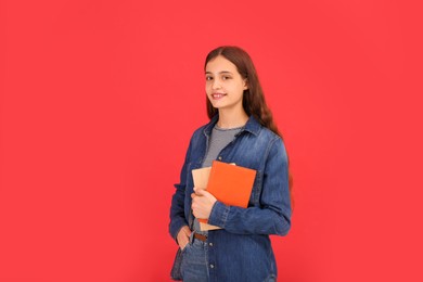 Teenage student with books on red background