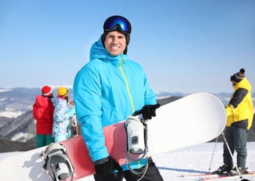 Photo of Man with snowboard at ski resort. Winter vacation