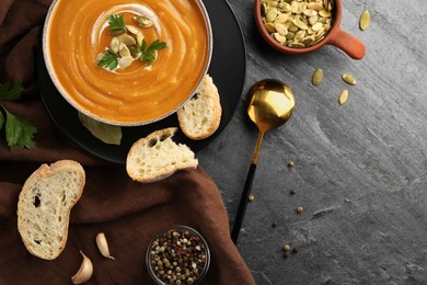 Photo of Flat lay composition with bowl of delicious pumpkin soup on grey textured table. Space for text