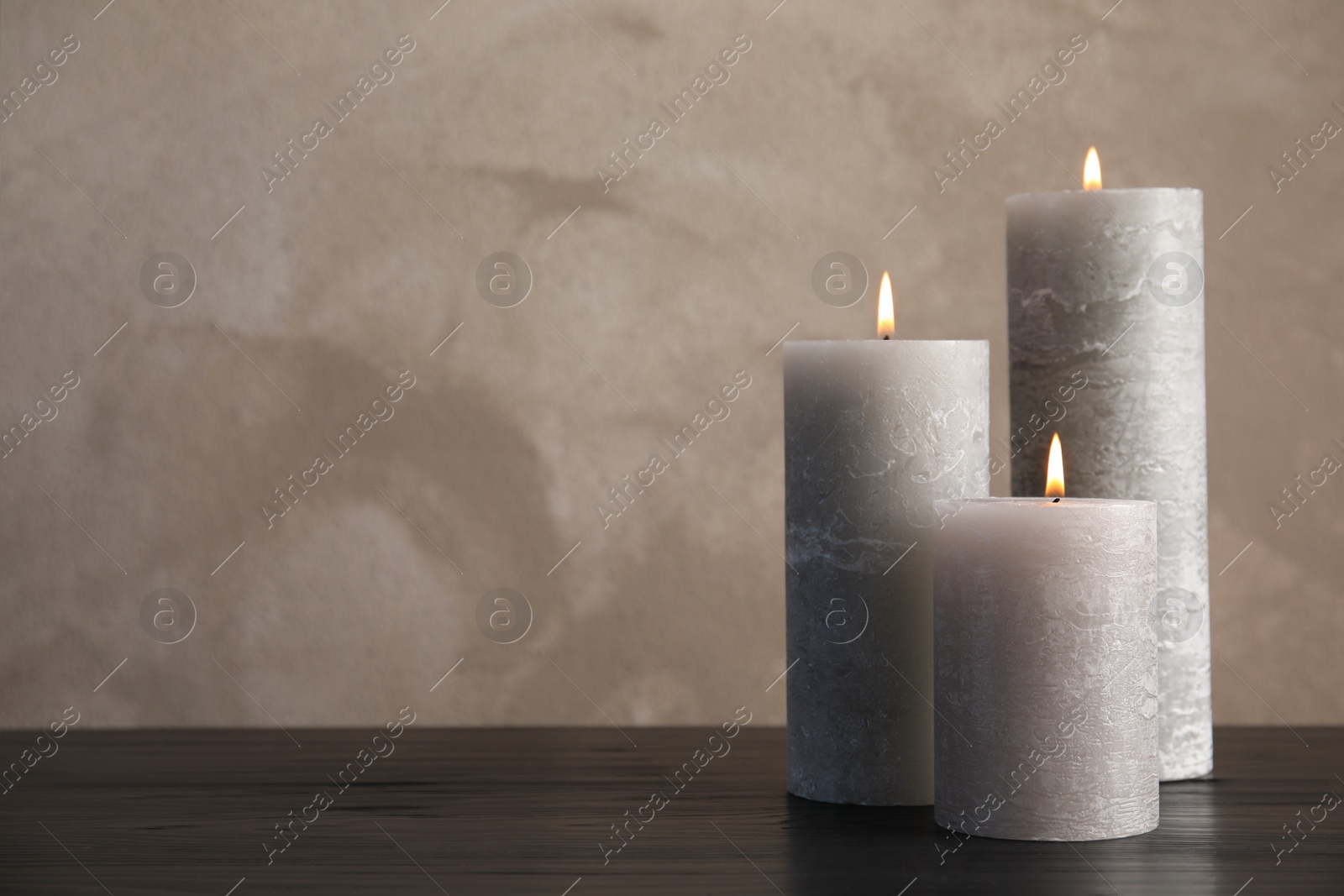 Photo of Burning candles on table against color background. Space for text