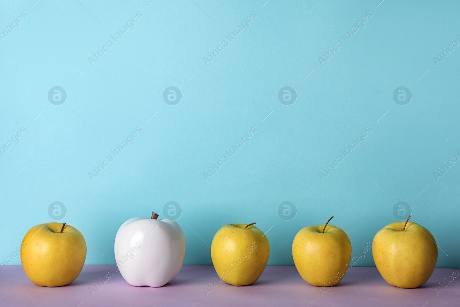 Photo of Row of fresh apples with decorative one on color background. Be different