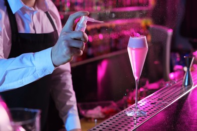 Bartender making fresh alcoholic cocktail at counter in bar, closeup