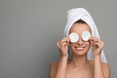 Photo of Smiling woman removing makeup with cotton pads on grey background. Space for text