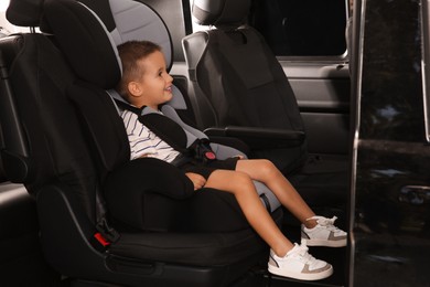 Photo of Little boy fastened with car safety belt in child seat