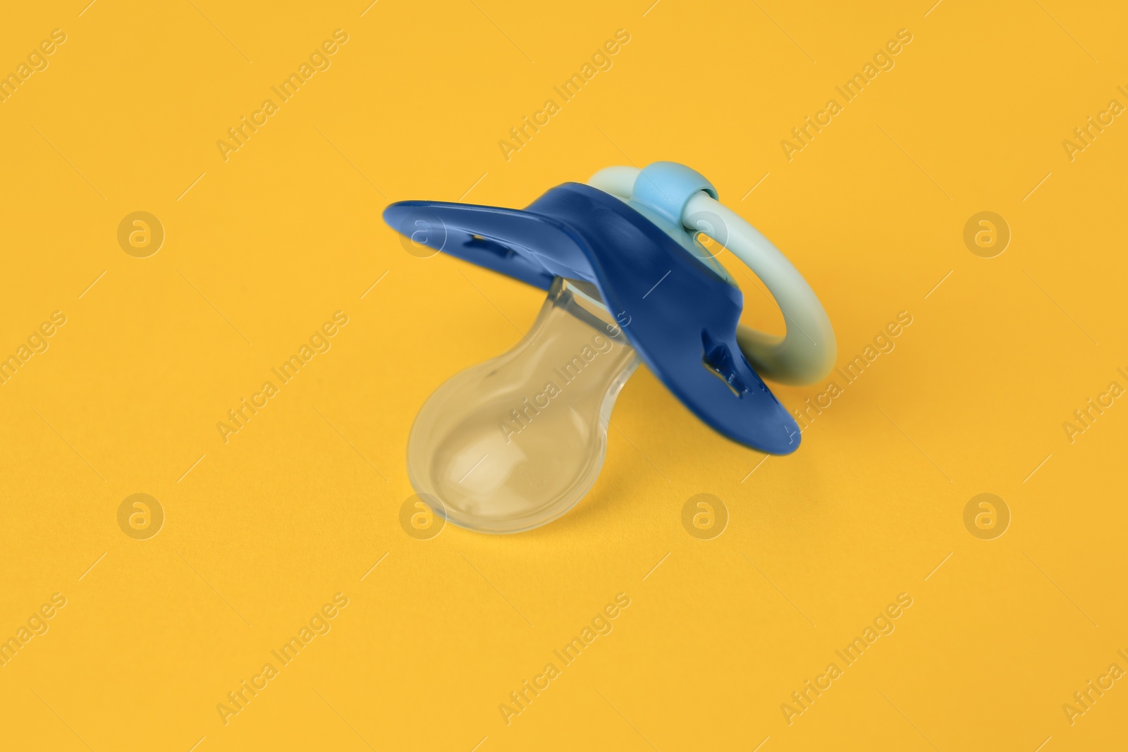 Photo of One blue baby pacifier on orange background