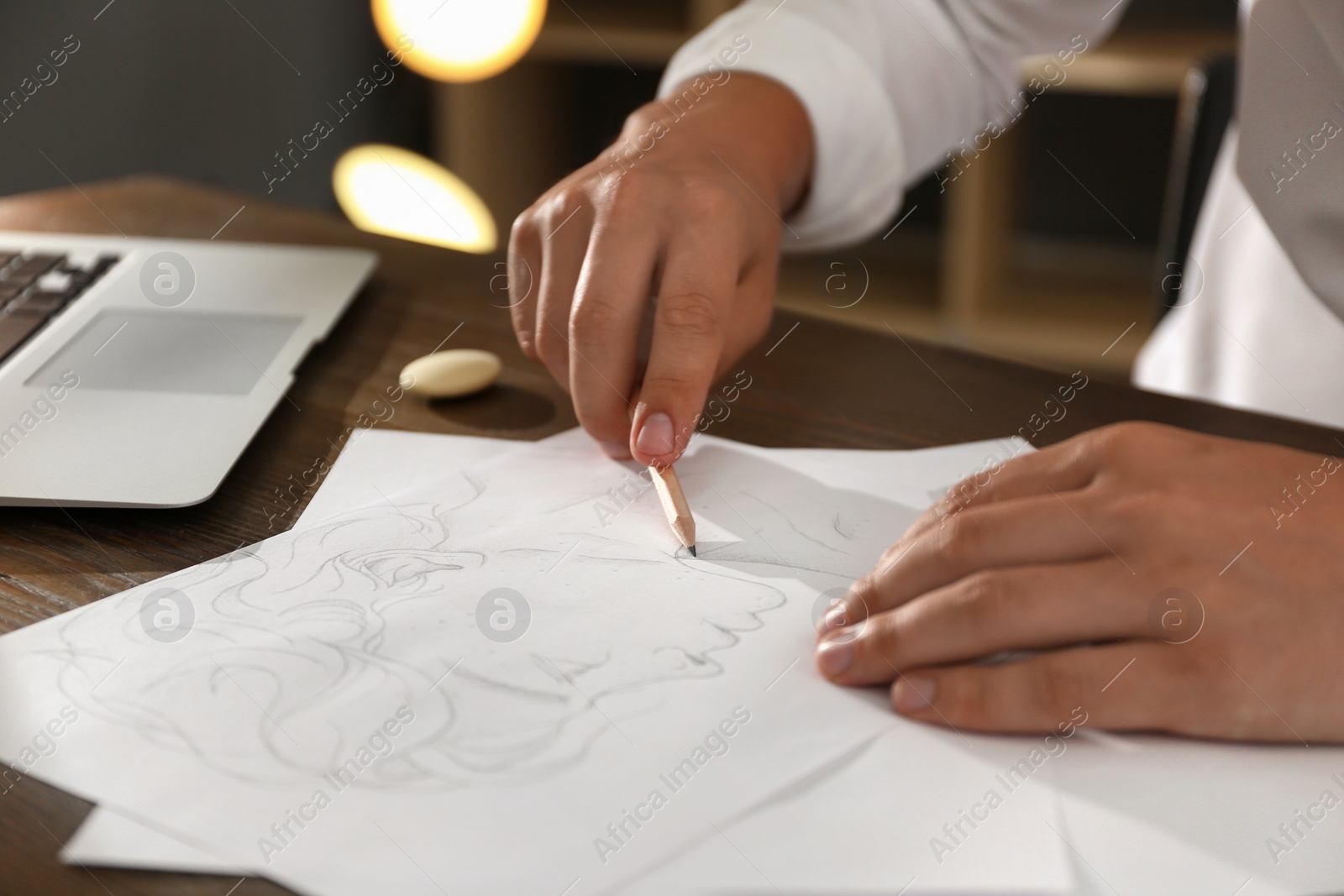 Photo of Man drawing portrait with pencil on sheet of paper at wooden table, closeup