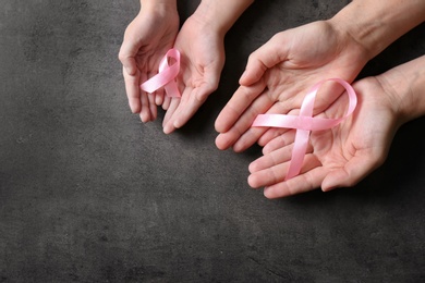 Woman and girl holding pink ribbons on grey background, top view with space for text. Breast cancer awareness