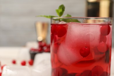 Photo of Tasty cranberry cocktail with ice cubes in glass on table, closeup. Space for text