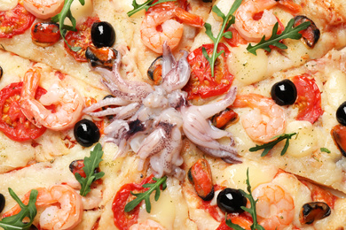 Tasty fresh pizza with seafood as background, closeup