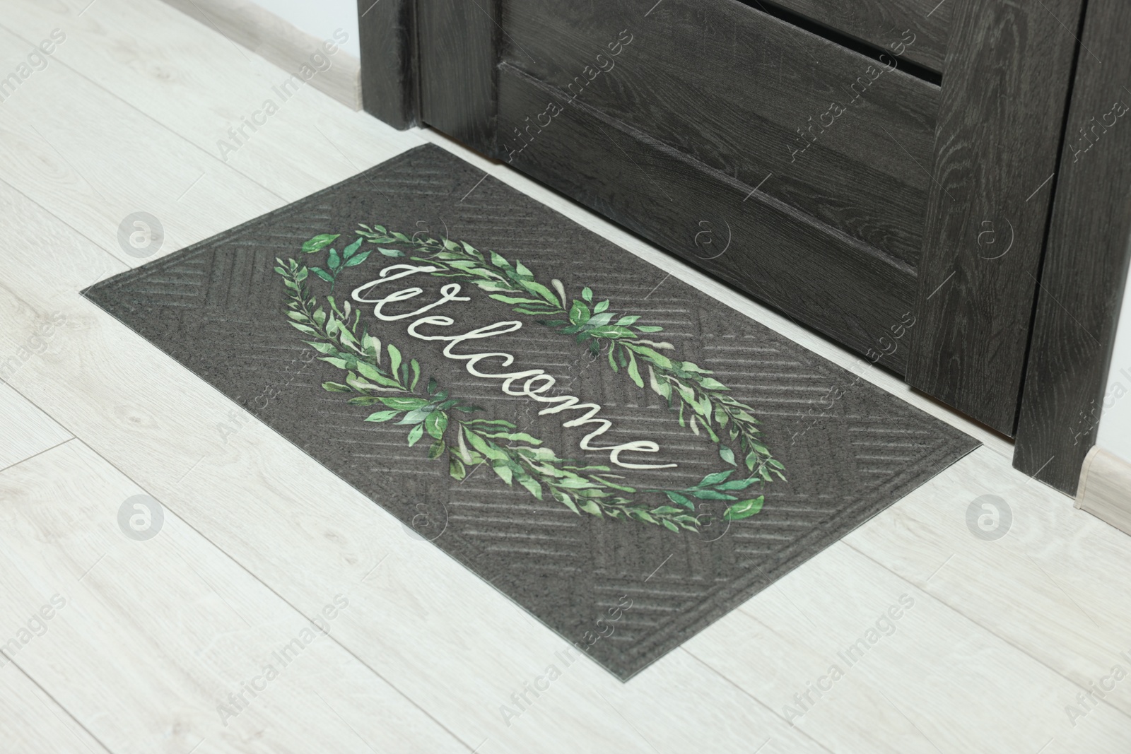 Photo of Doormat with word Welcome on white floor near entrance