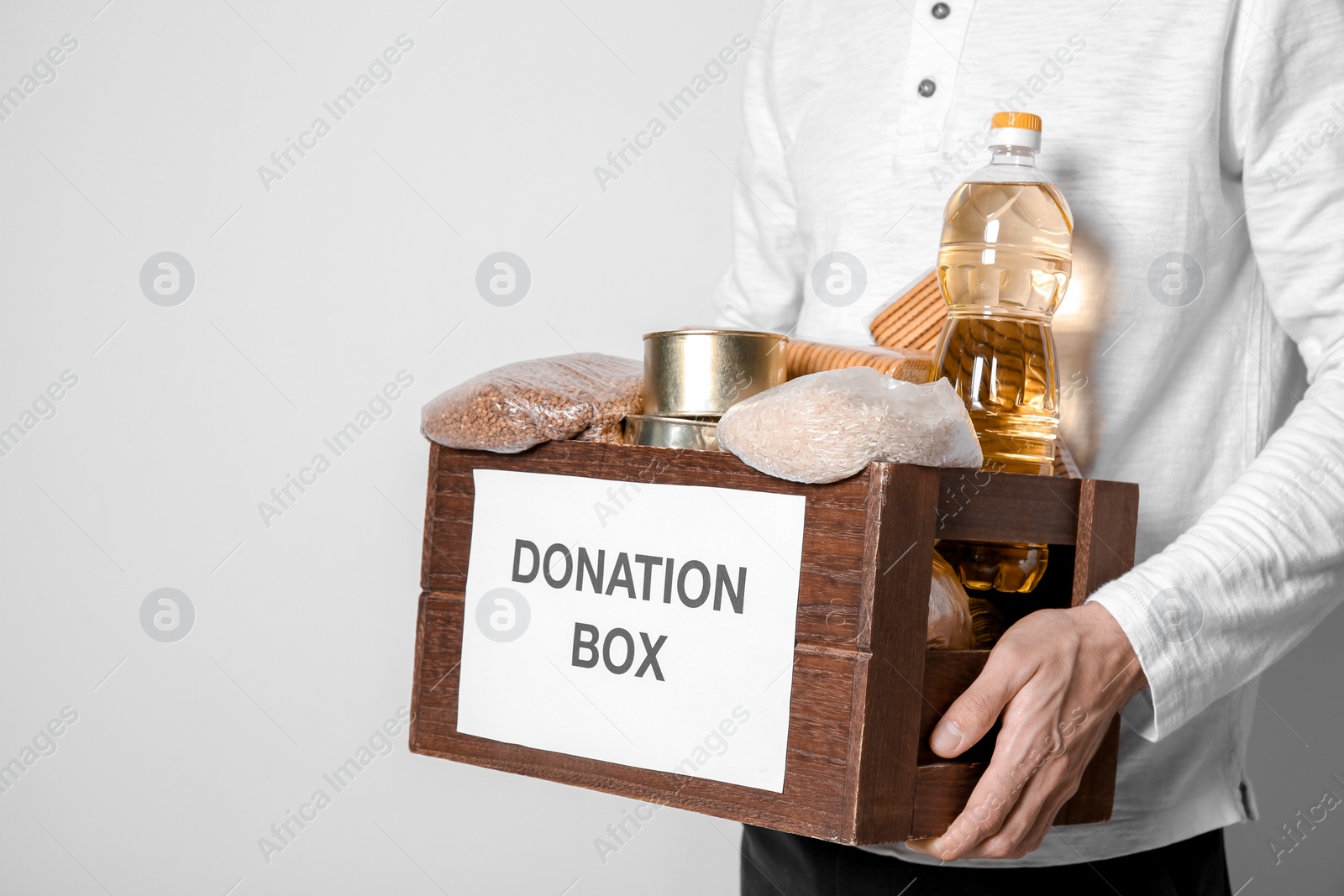 Photo of Male volunteer holding donating box with food against white background