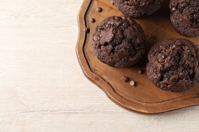 Delicious chocolate muffins on white wooden table, top view. Space for text