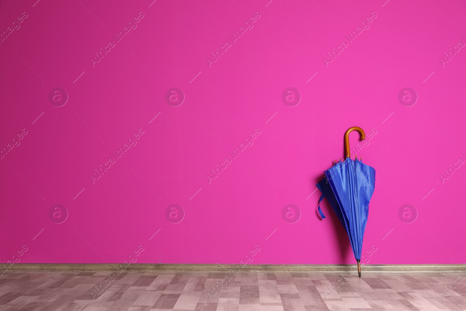 Photo of Beautiful umbrella on floor near color wall with space for design