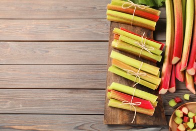 Many cut rhubarb stalks on wooden table, above view. Space for text