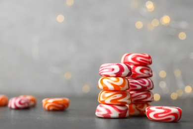 Photo of Stacked tasty hard candies on grey table. Space for text