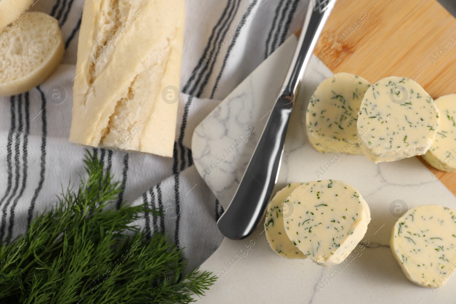 Photo of Tasty butter, dill, bread and knife on table, top view