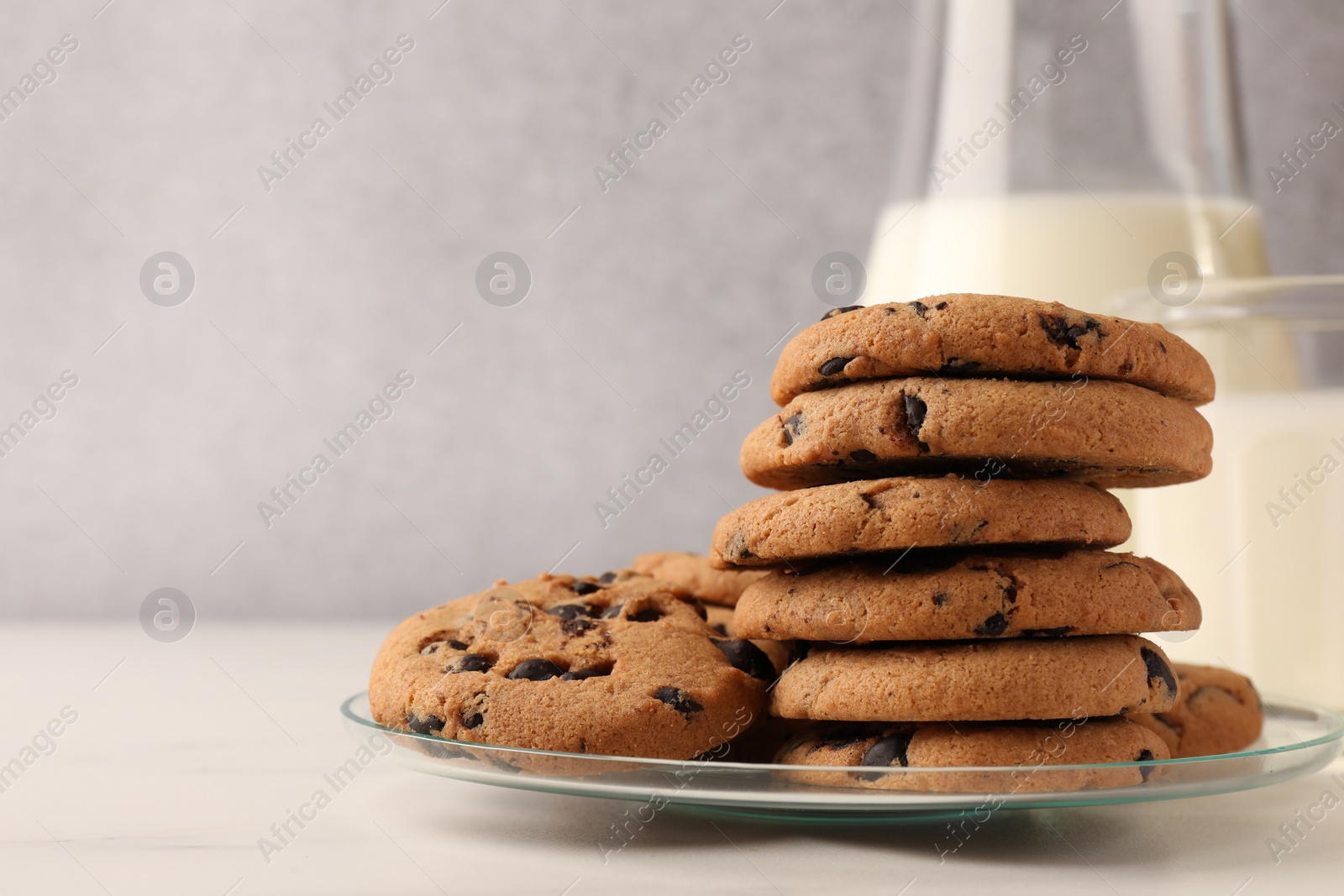 Delicious chocolate chip cookies and milk on white marble table. Space for text Photo of Delicious chocolate chip cookies and milk on white marble table. Space for text