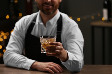Photo of Bartender with glass of whiskey at bar counter indoors, closeup. Space for text