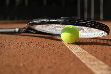 Photo of Tennis ball and racket on clay court, closeup