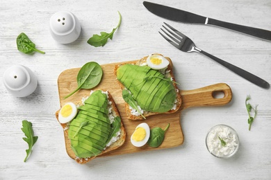 Photo of Flat lay composition with avocado toasts on white wooden table